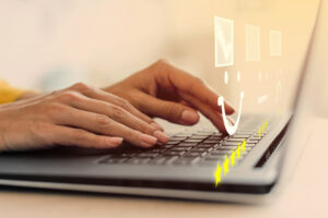 Nahaufnahme von Händen, die auf einer Laptop-Tastatur tippen, mit grafischen Symbolen von Smileys und Sternen darüber liegend, die auf ein Bewertungssystem hinweisen. Marke anmelden.